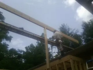 Carpenter setting a ridge beam over a new addition frame — Ice Dam Removal by Roofing Brothers in Tougaloo