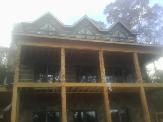 Dormers and porch framing on a large log home under construction — Roof Coating work by our crew in Tougaloo