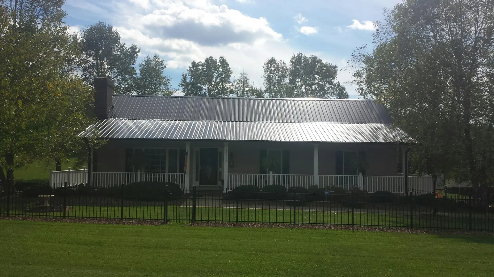 Gray metal roof on a brick ranch with a full width front porch — Gutter Guard Installation work by our crew in Tougaloo