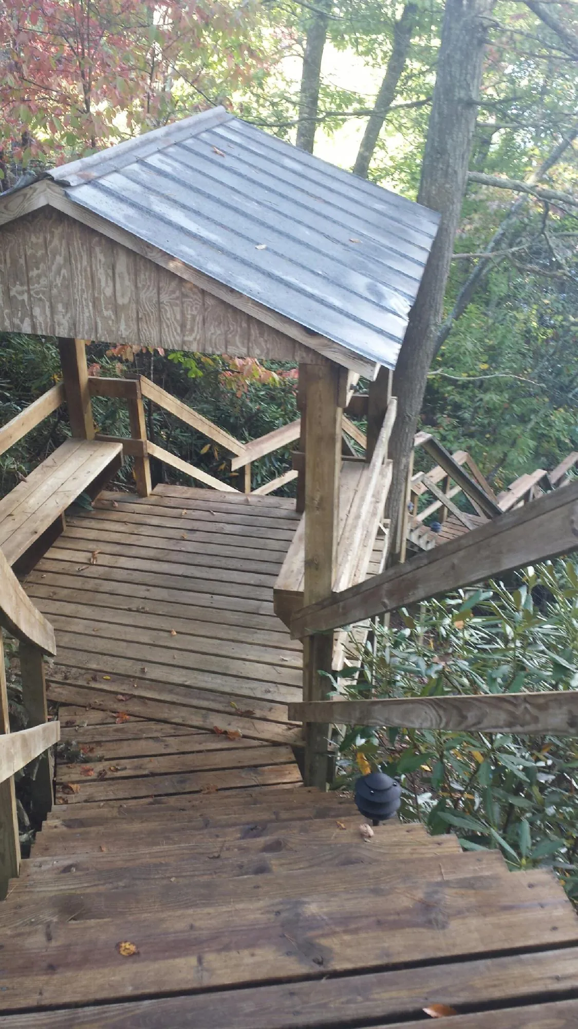 Metal roofed shelter over wooden steps on a wooded walkway — Skylight Repair & Installation work by our crew in Tougaloo