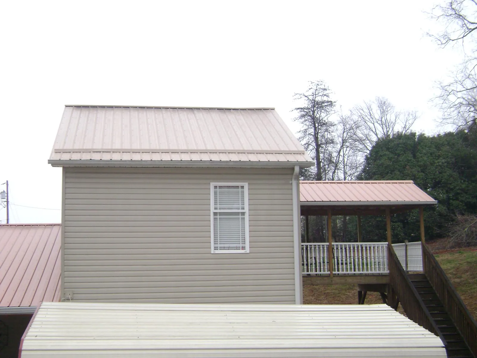 Tan metal roofs on a two story addition and attached porch, from a Roof Replacement job in Tougaloo