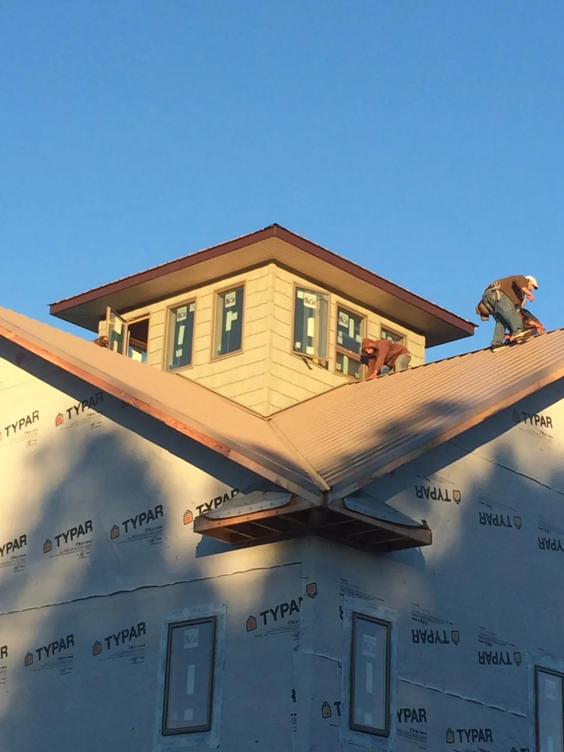 Roofers working around a rooftop cupola on a new metal roof at sunset — Roof Waterproofing in Tougaloo by Roofing Brothers